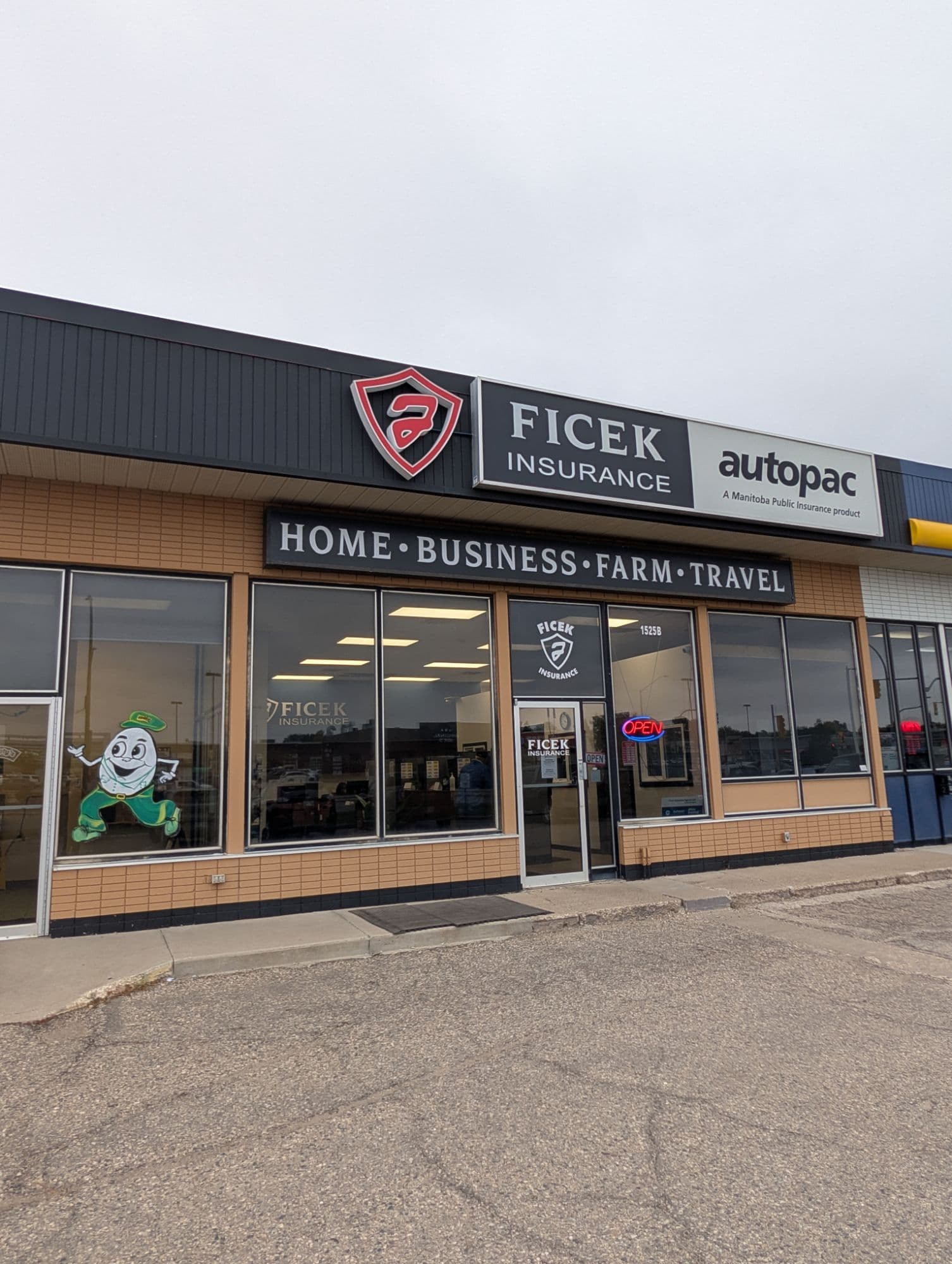 The 1525B storefront: the Ficek Insurance shield and Autopac sign above a black sign reading Home, Business, Farm, Travel, with the glass entrance door below.