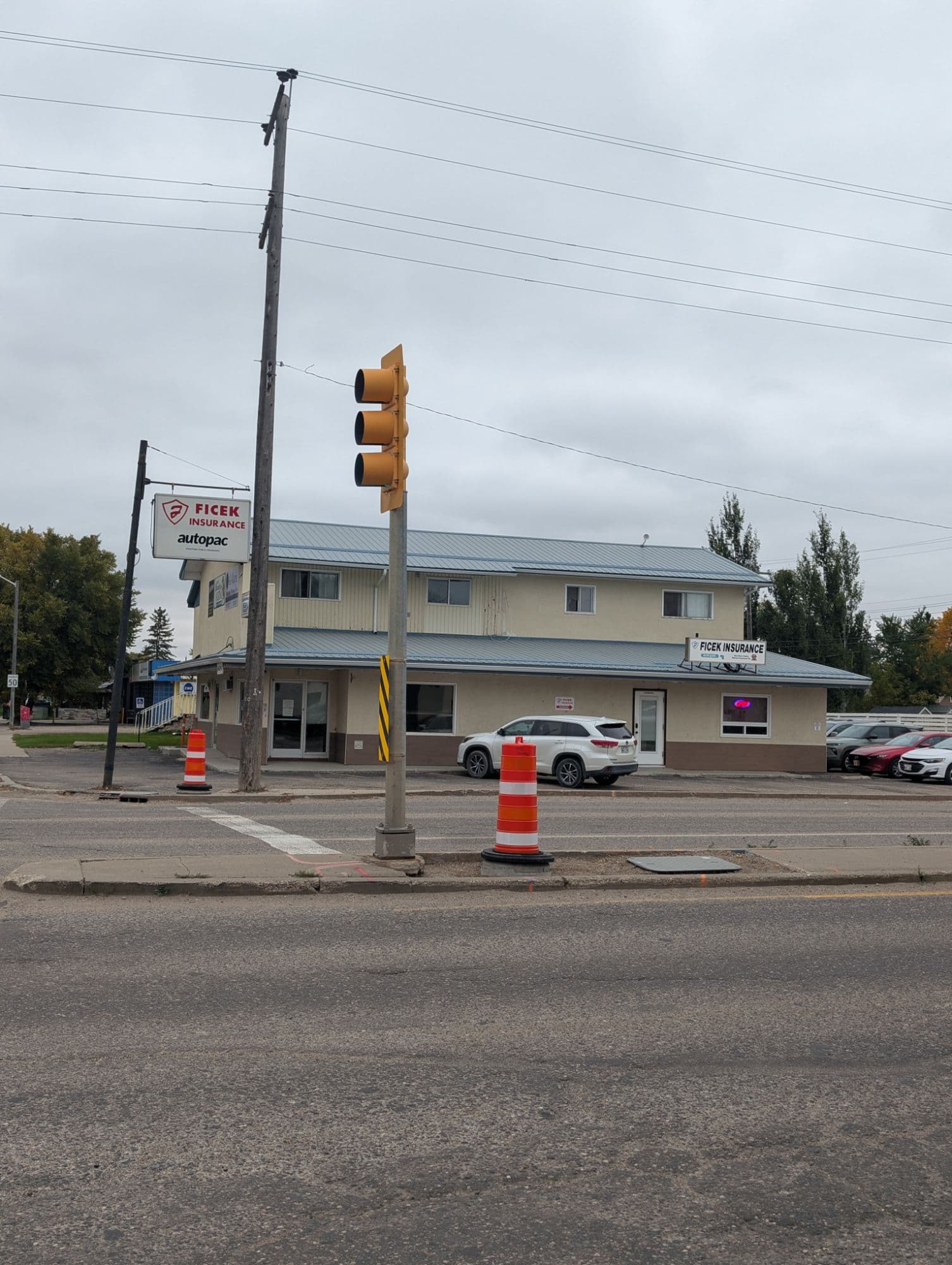 The 1439 1st Street office viewed from across the street, showing the Ficek Insurance Autopac sign, the front entrance and the client parking lot beside the building.